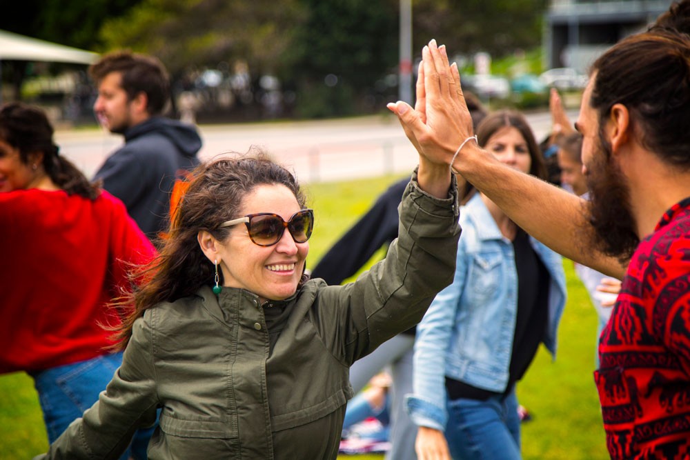 un chico y una chica morenos chocándose la mano en una clase de yoga para aguantar el equilibrio